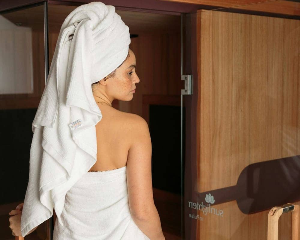 Client wrapped in towels beside the sauna door