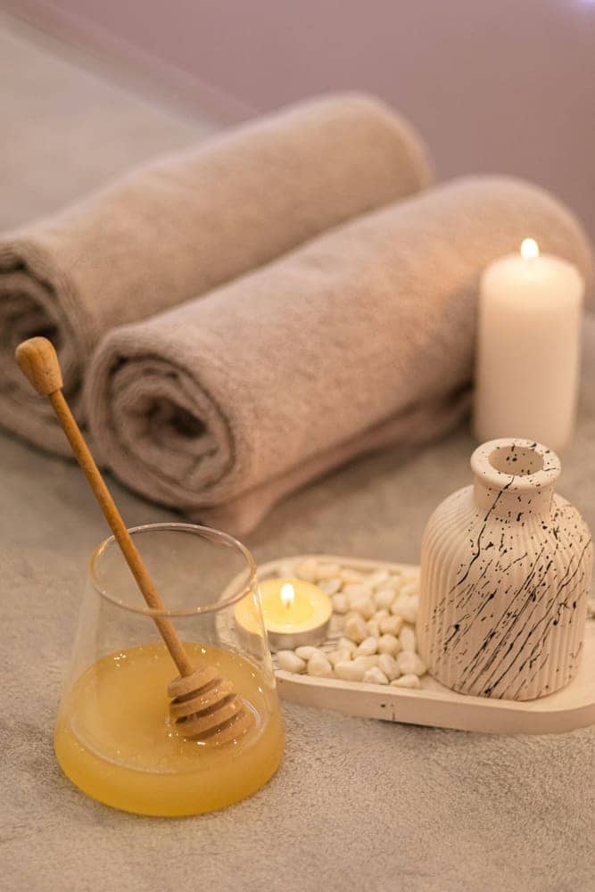 Rolled towels, candle, and honey on a treatment table