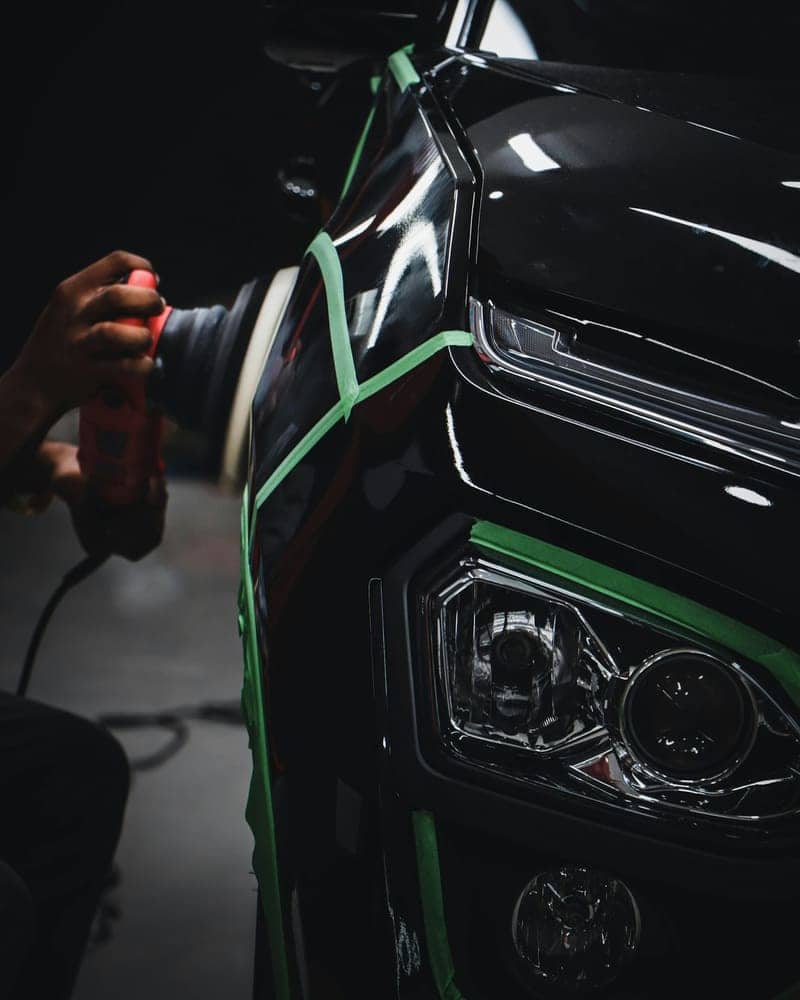 Headlight masked with tape for machine polishing