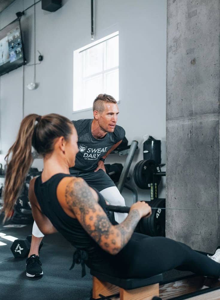 Trainer coaching a client through a cable row