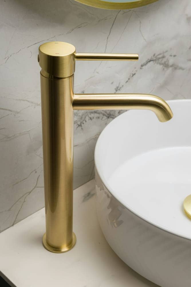 New brass faucet installed over a white vessel sink